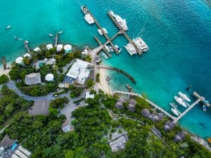 Staniel Cay Yacht Club Aerial view of a tropical marina near Staniel Cay Resort, with several boats docked at piers, surrounded by turquoise water and lush greenery. Vacation Rentals and Resort on Staniel Cay Exuma