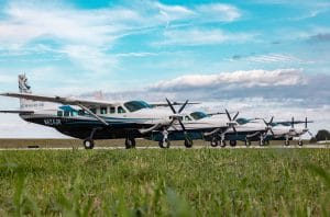 Staniel Cay Yacht Club Four small airplanes are parked in a row on a grassy airfield under a partly cloudy sky, ready to whisk you away to the tropical paradise of Staniel Cay Resort. Vacation Rentals and Resort on Staniel Cay Exuma