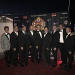 A group of men in tuxedos standing on a red carpet at Staniel Cay.