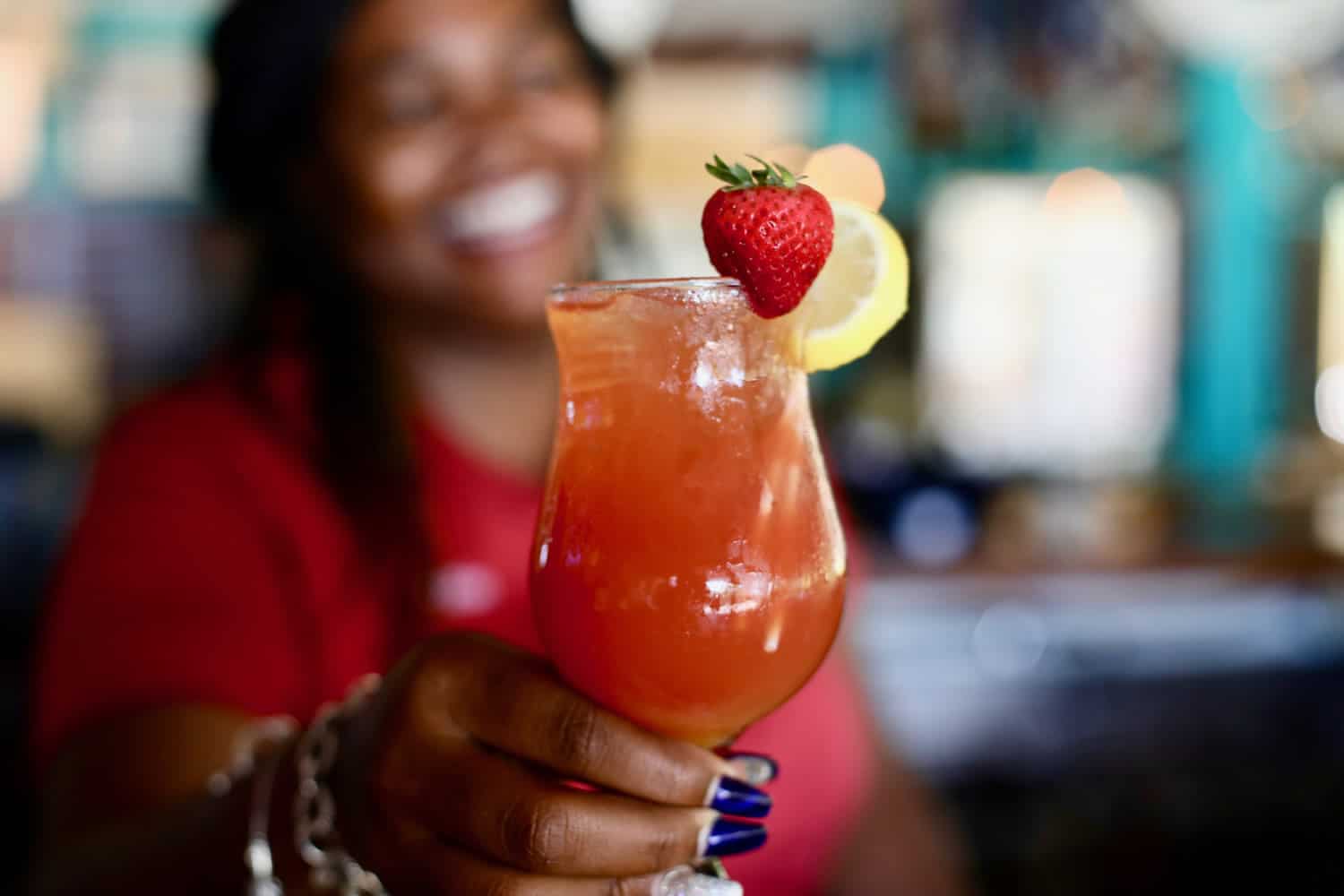 A bartender at Staniel Cay Yacht Club holds up a strawberry drink.