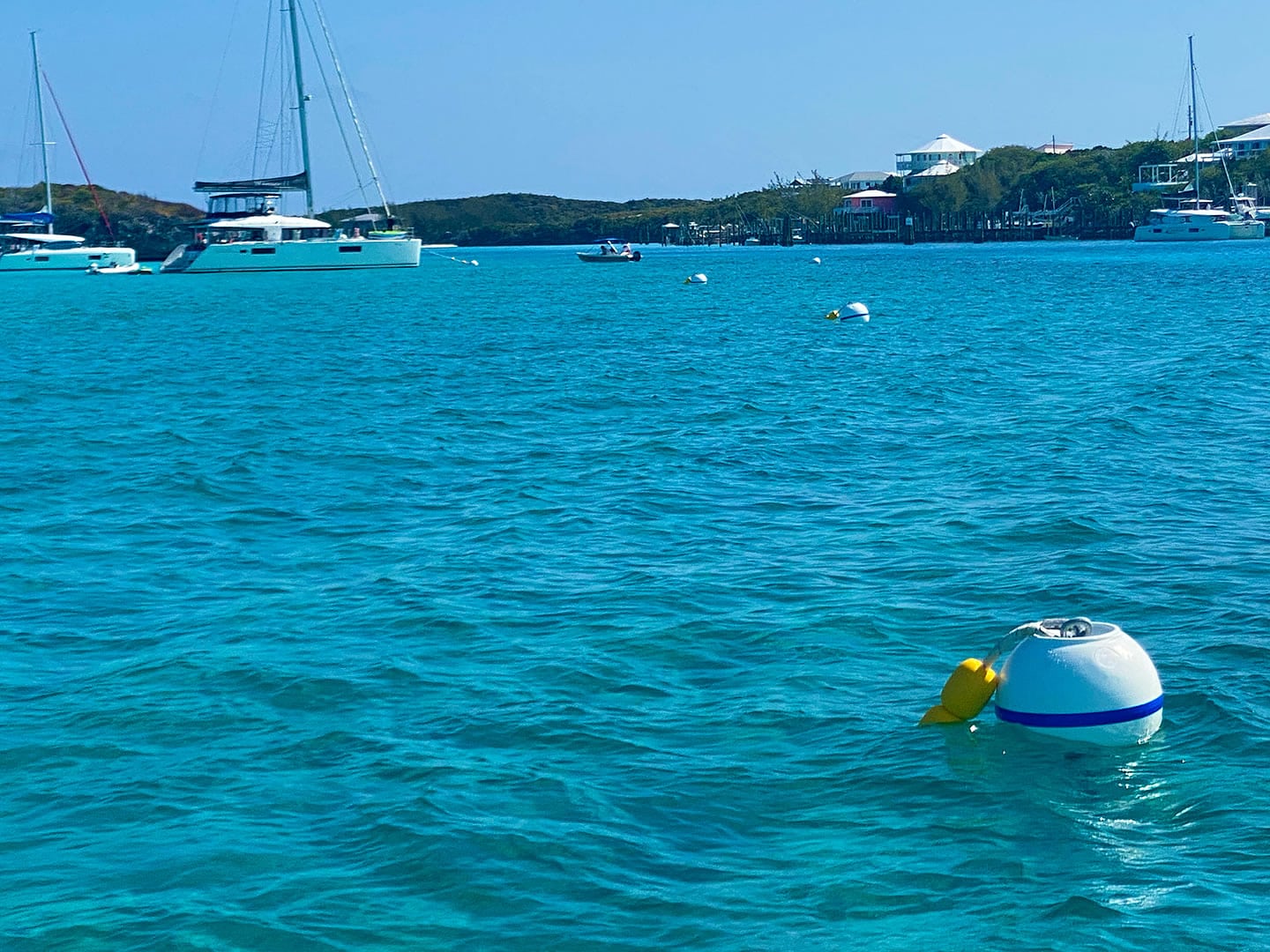 A boat is floating near a buoy in the turquoise waters of Staniel Cay.