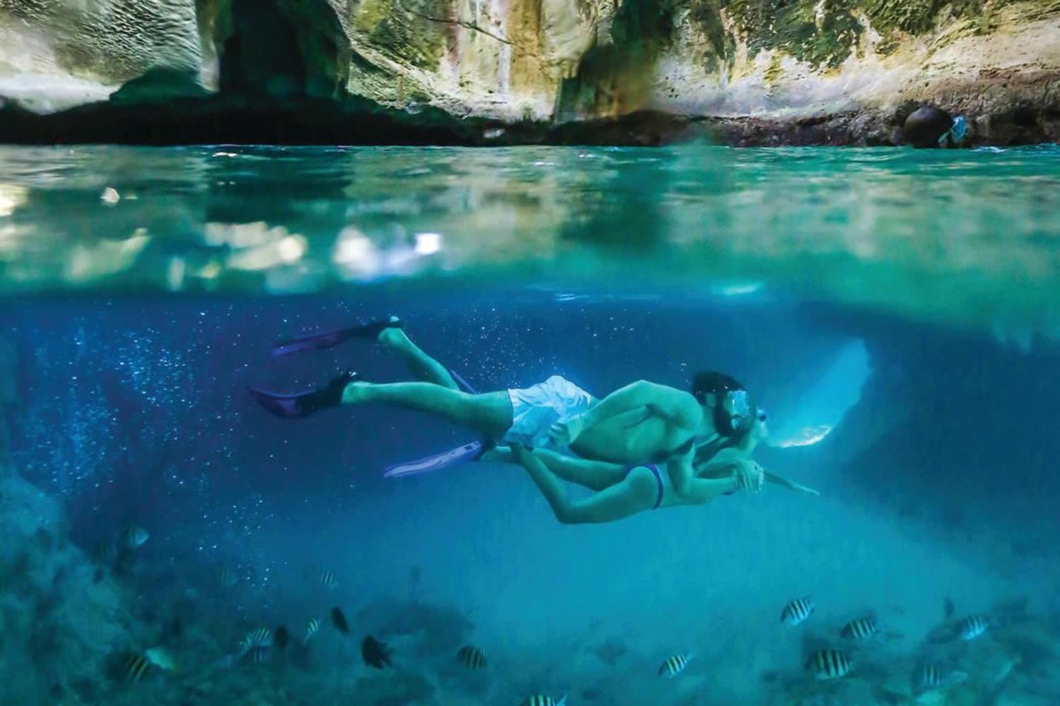 A couple snorkling near a cave in The Bahamas.