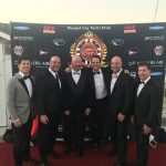 A group of men in tuxedos standing on a red carpet at Staniel Cay, exuding elegance and sophistication.