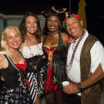 A group of people in pirate costumes posing for a photo at the Staniel Cay Yacht Club in The Bahamas.
