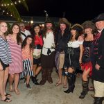 A group of people in pirate costumes posing for a photo during their vacation at Staniel Cay Yacht Club in The Bahamas.