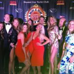 A group of people posing for a photo at Staniel Cay Yacht Club on a red carpet.
