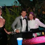 A group of people posing in front of a roulette table at Staniel Cay Yacht Club.