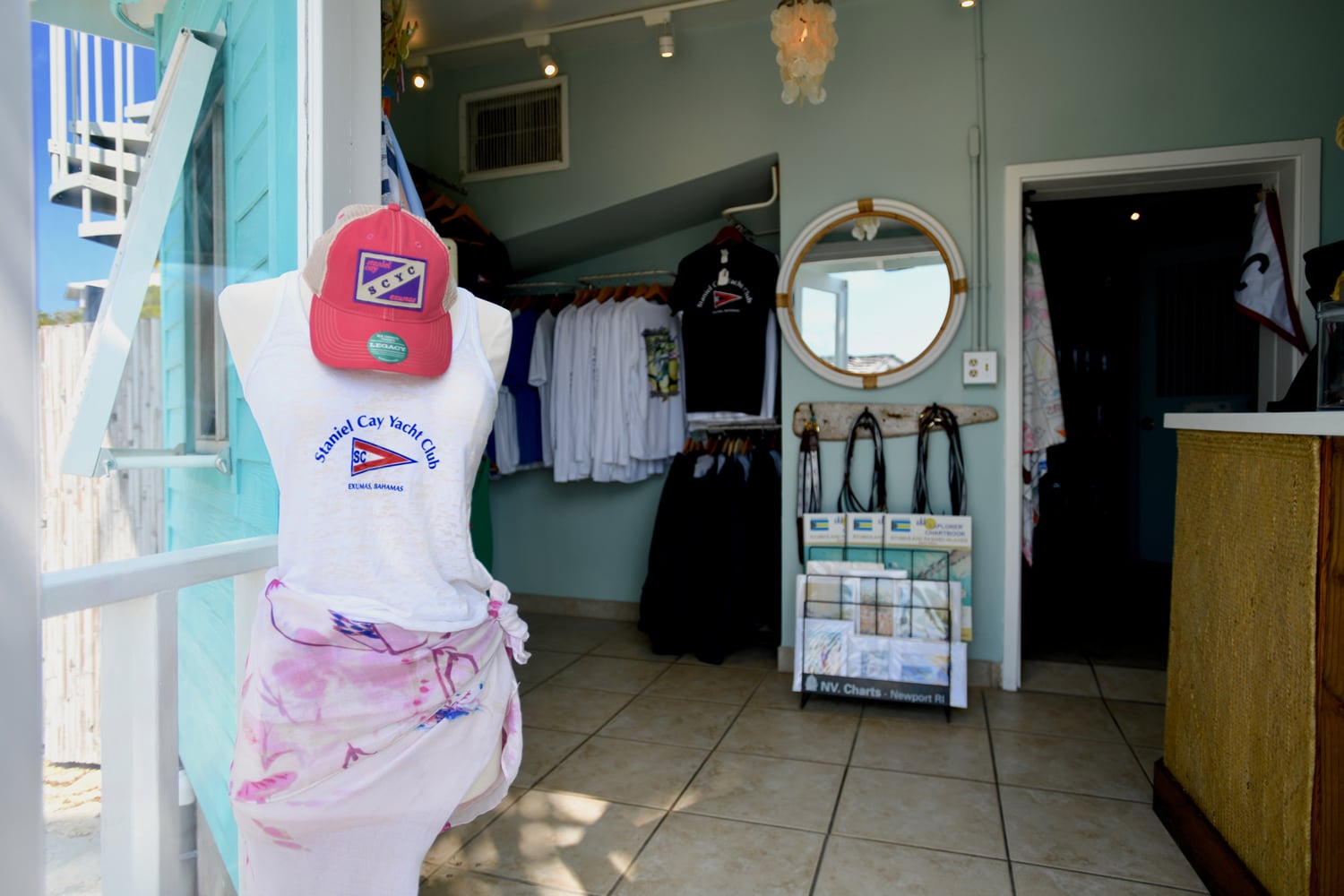 A mannequin wearing a hat stands proudly in front of the Staniel Cay Yacht Club store.