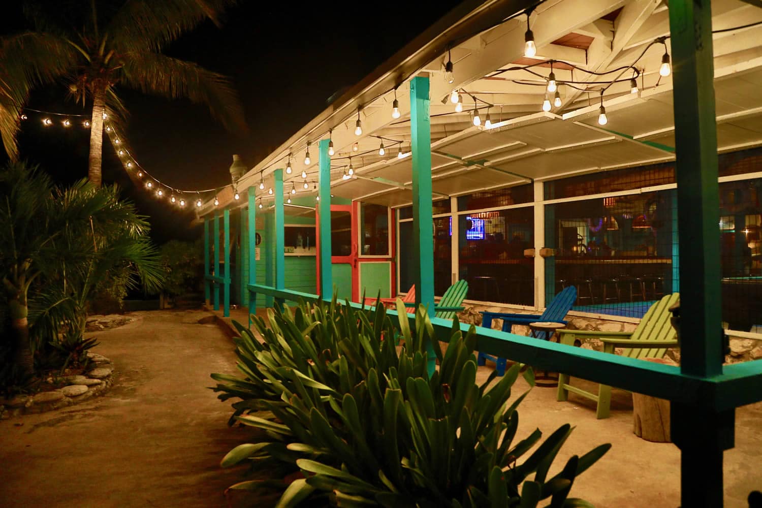 A patio at night with palm trees and string lights in Staniel Cay.
