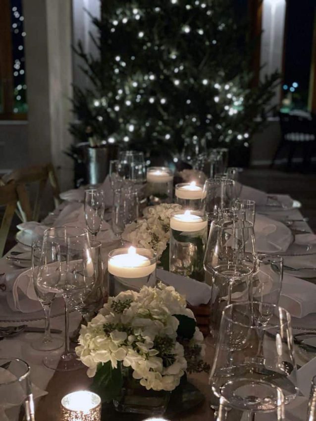 A table set with candles and flowers in front of a Staniel Cay Christmas tree.