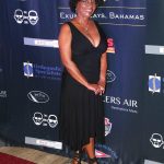 A woman in a black dress standing on a red carpet at Staniel Cay.