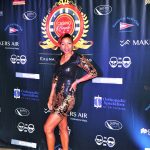 A woman in a black dress striking a pose on the red carpet at Staniel Cay Yacht Club in The Bahamas.
