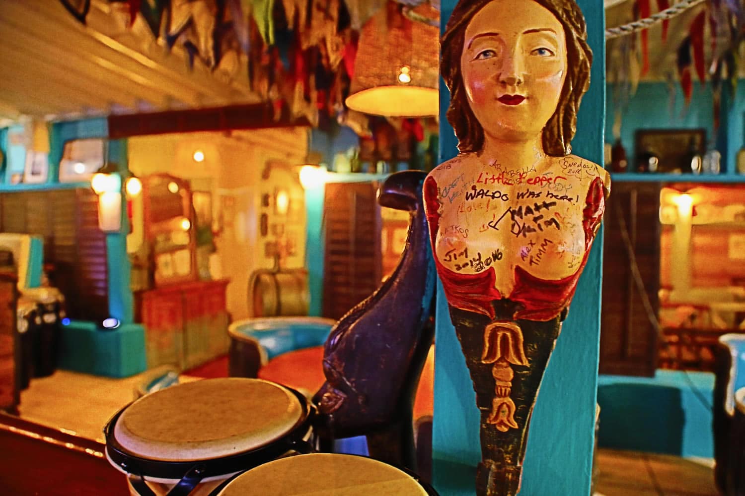A wooden statue of a woman sits on a pole in a bar in Staniel Cay, The Bahamas.