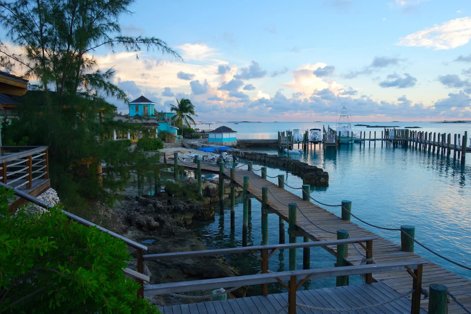 A wooden walkway leading to a dock in the middle of the ocean, nestled in the breathtaking scenery of Staniel Cay, The Bahamas.