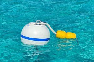 A yellow and white buoy floating in the clear blue water near Staniel Cay Yacht Club.