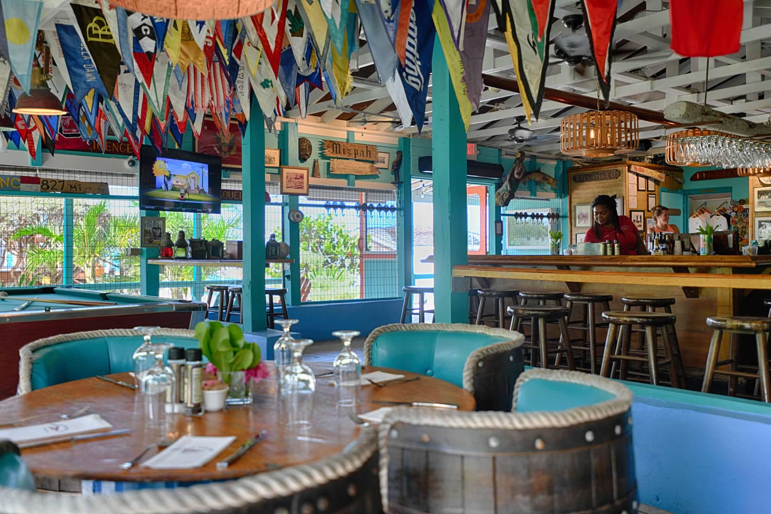 The interior of Staniel Cay Yacht Club, a restaurant with flags hanging from the ceiling.