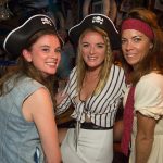 Three women in pirate hats posing for a photo at Staniel Cay Yacht Club in The Bahamas.