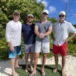 Four men posing for a picture at Staniel Cay Yacht Club on a golf course.