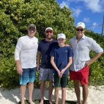 Three men and a boy posing for a photo at Staniel Cay Yacht Club on a golf course.