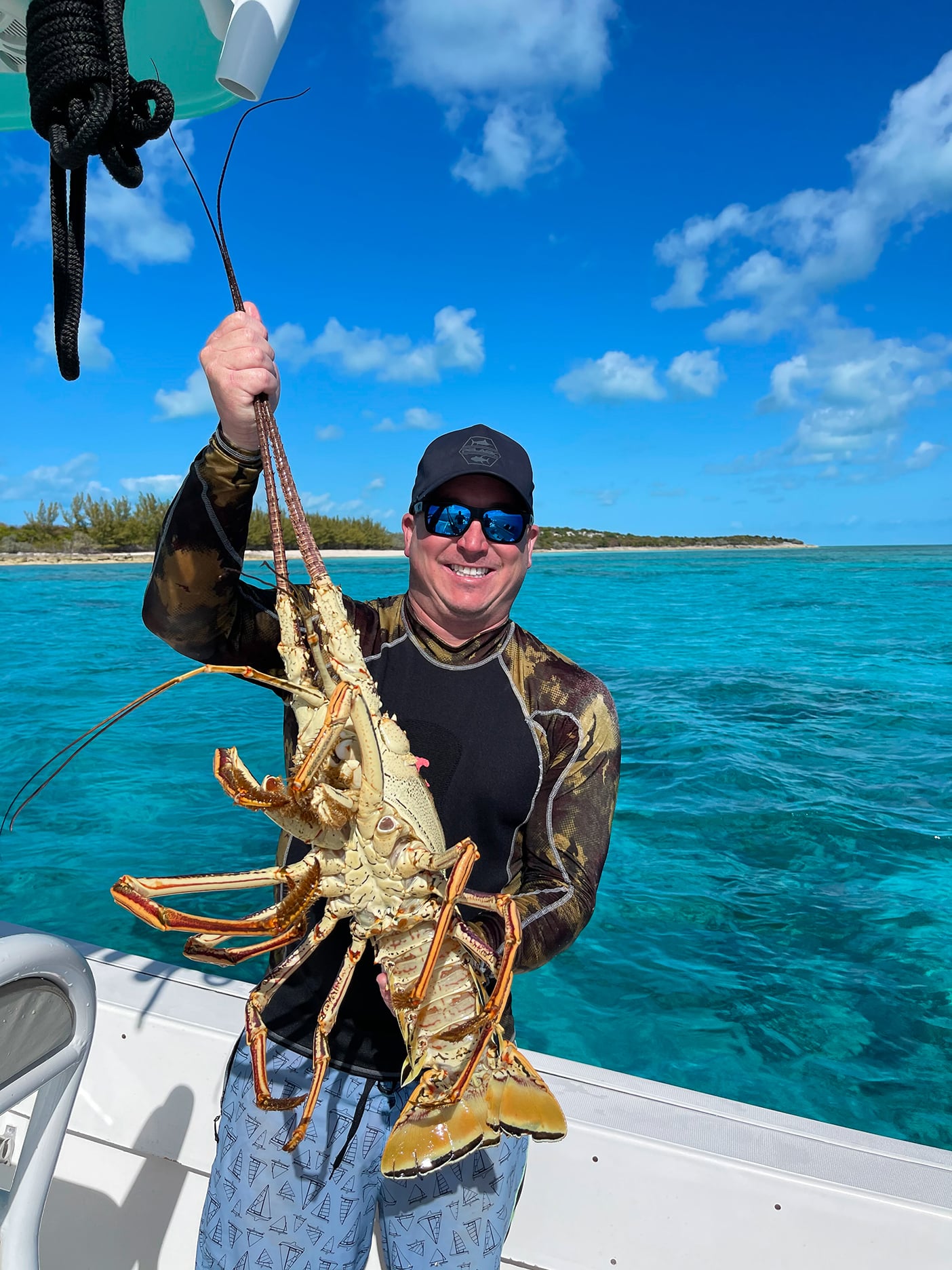 A man holding up a lobster on a boat at Staniel Cay.