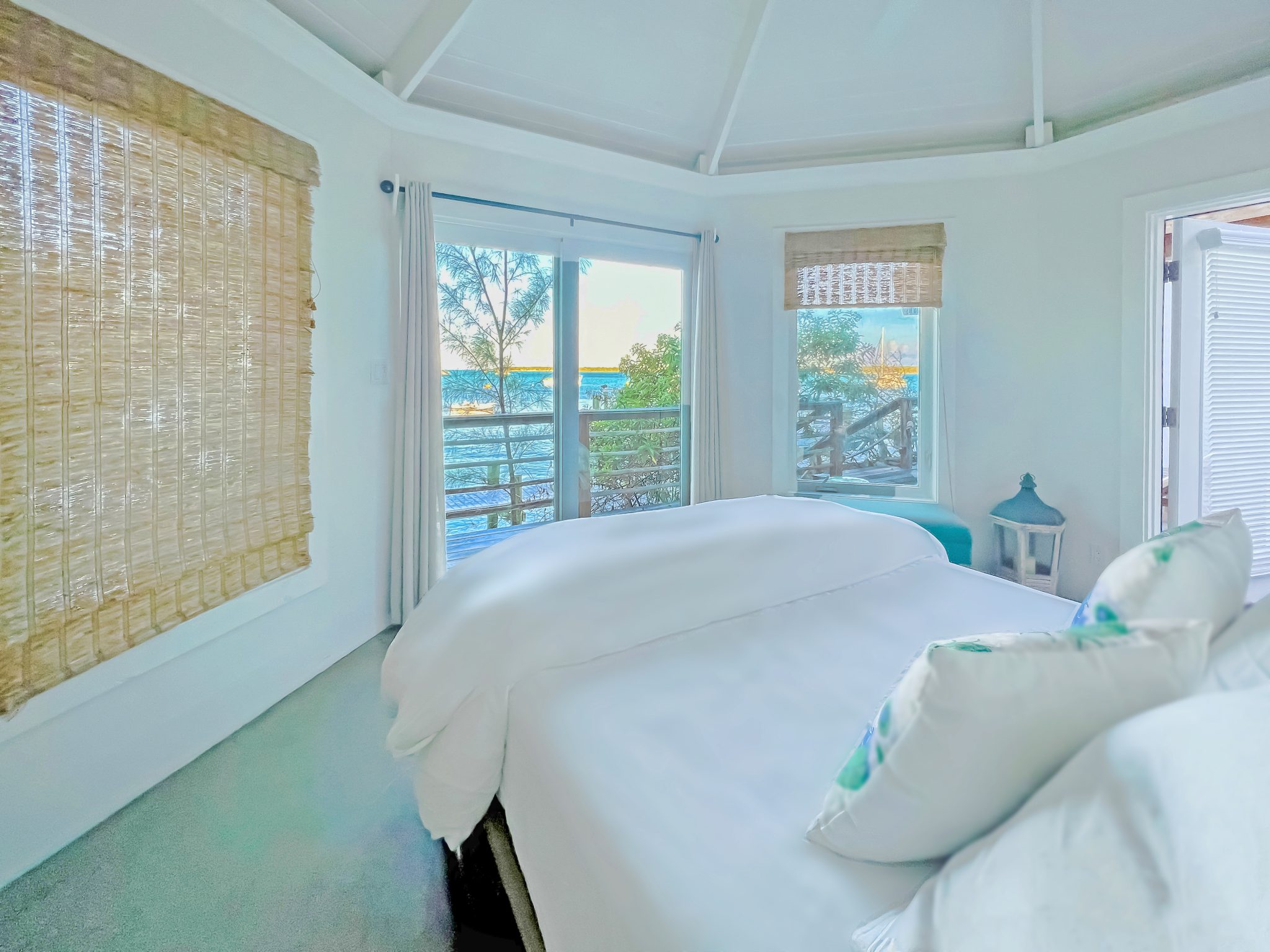Staniel Cay Vacation Rentals offers a serene bedroom with a white bed and an exquisite view of the ocean.