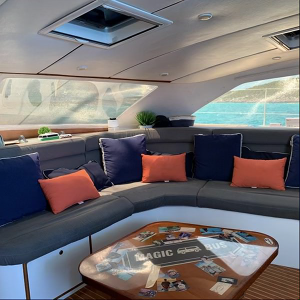 Staniel Cay Yacht Club The cozy boat lounge features a U-shaped couch adorned with blue and orange pillows, a wooden table playfully decorated with stickers, and stunning views of the sea. It's the perfect setting for your yacht charters along picturesque coastlines. Vacation Rentals and Resort on Staniel Cay Exuma