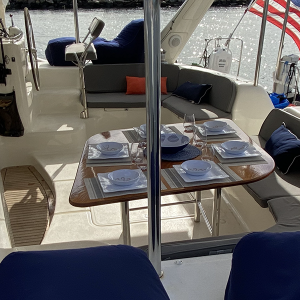 Staniel Cay Yacht Club A yacht's outdoor seating area offers a set dining table with plates, napkins, and glasses. An American flag waves proudly at the back as you enjoy stunning water views. Perfect for luxury yacht charters, this setting promises an unforgettable escape into serenity. Vacation Rentals and Resort on Staniel Cay Exuma